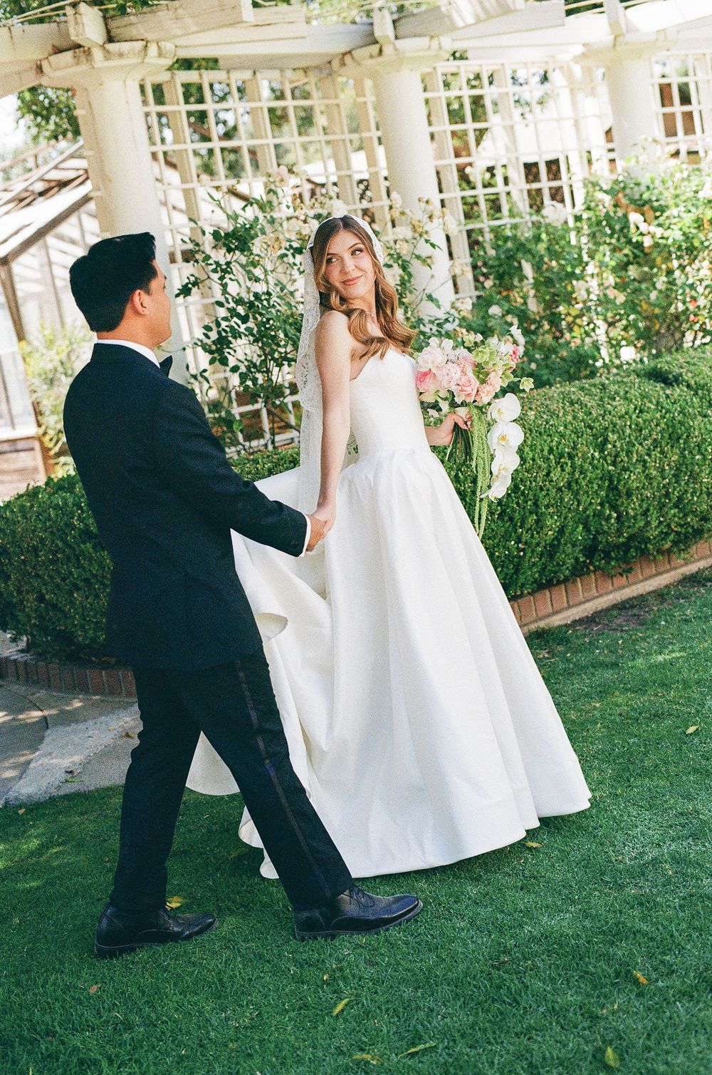 A candid, documentary-style 35mm film photograph of a modern couple walking through a luxury wedding venue, serving CA and NC.