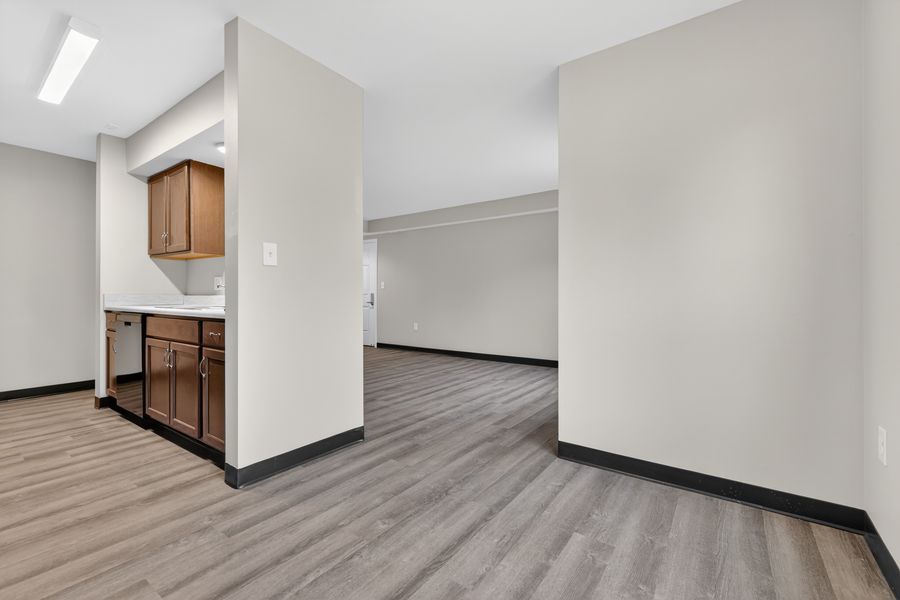 Open living area with hardwood floors, brown cabinets, and neutral walls in a modern apartment.