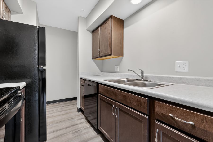 Modern kitchen with dark wood cabinets, double sink, and light countertops.