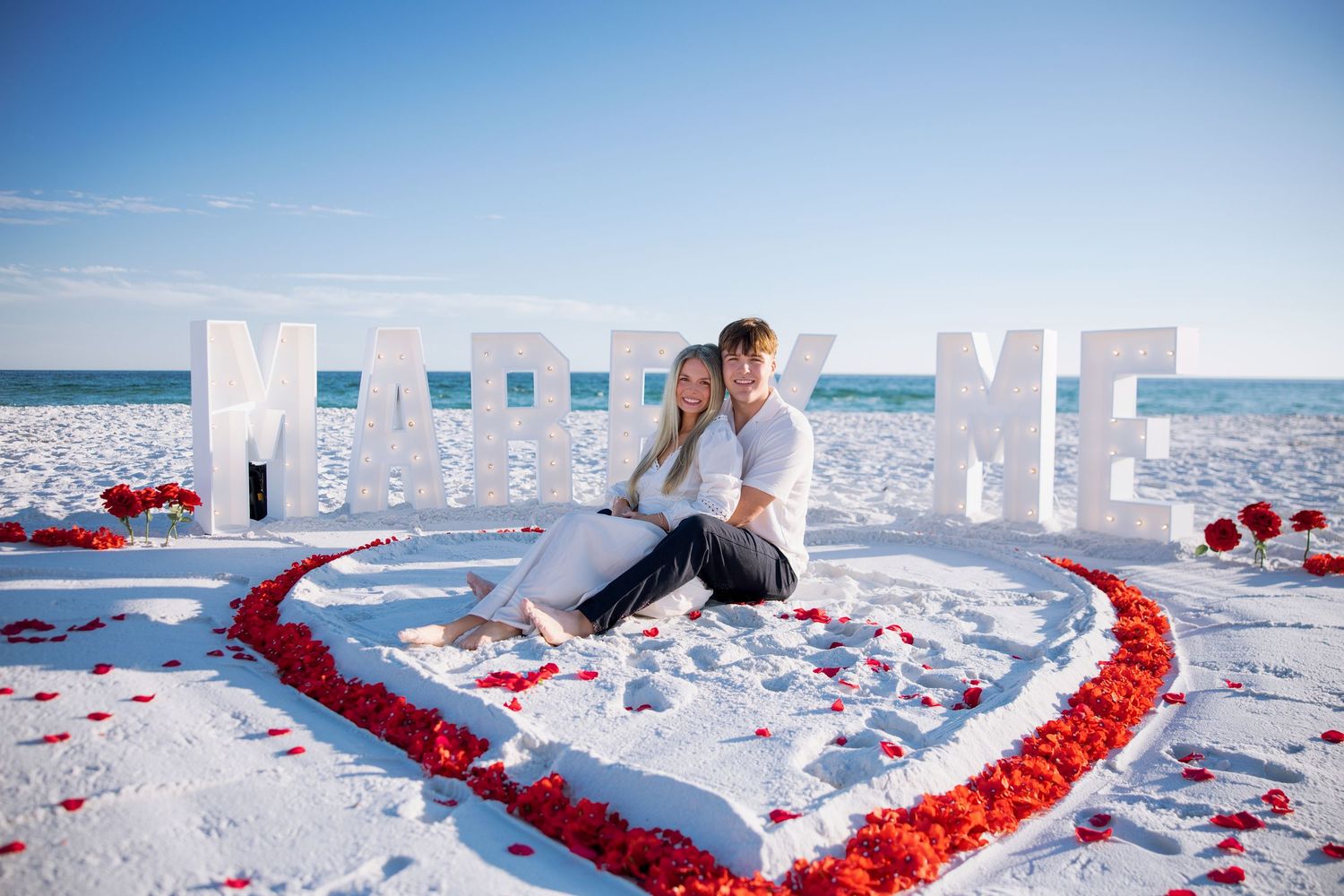 newly engaged couple cuddling on the beach