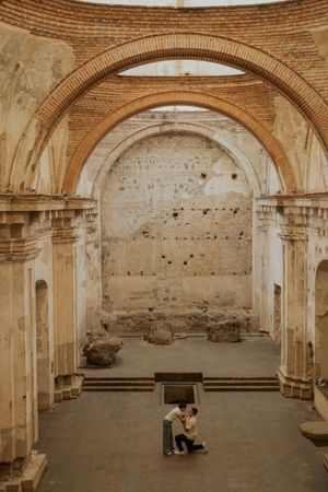 Couple embracing inside ancient brick arch ruins of a historic church in Antigua, Guatemala.