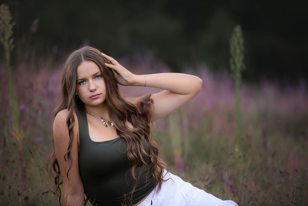Senior editorial portrait at Island Lake, Brighton Michigan; girl sitting in flower field with cinematic mood by South Lyon, MI photographer