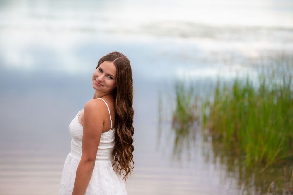 Senior sunset portrait at Island Lake, Brighton Michigan; girl standing in lake with cinematic aesthetic by South Lyon, MI photographer