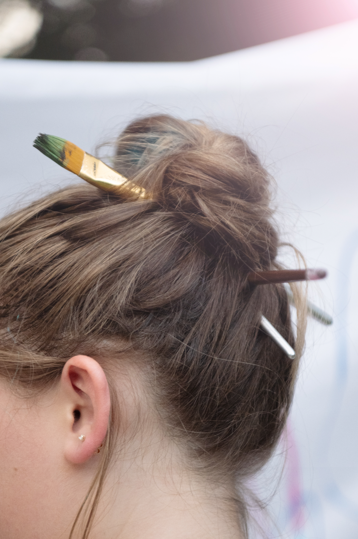 Woman's updo hairstyle secured with a paintbrush and bobby pins, showing creative hair accessories.