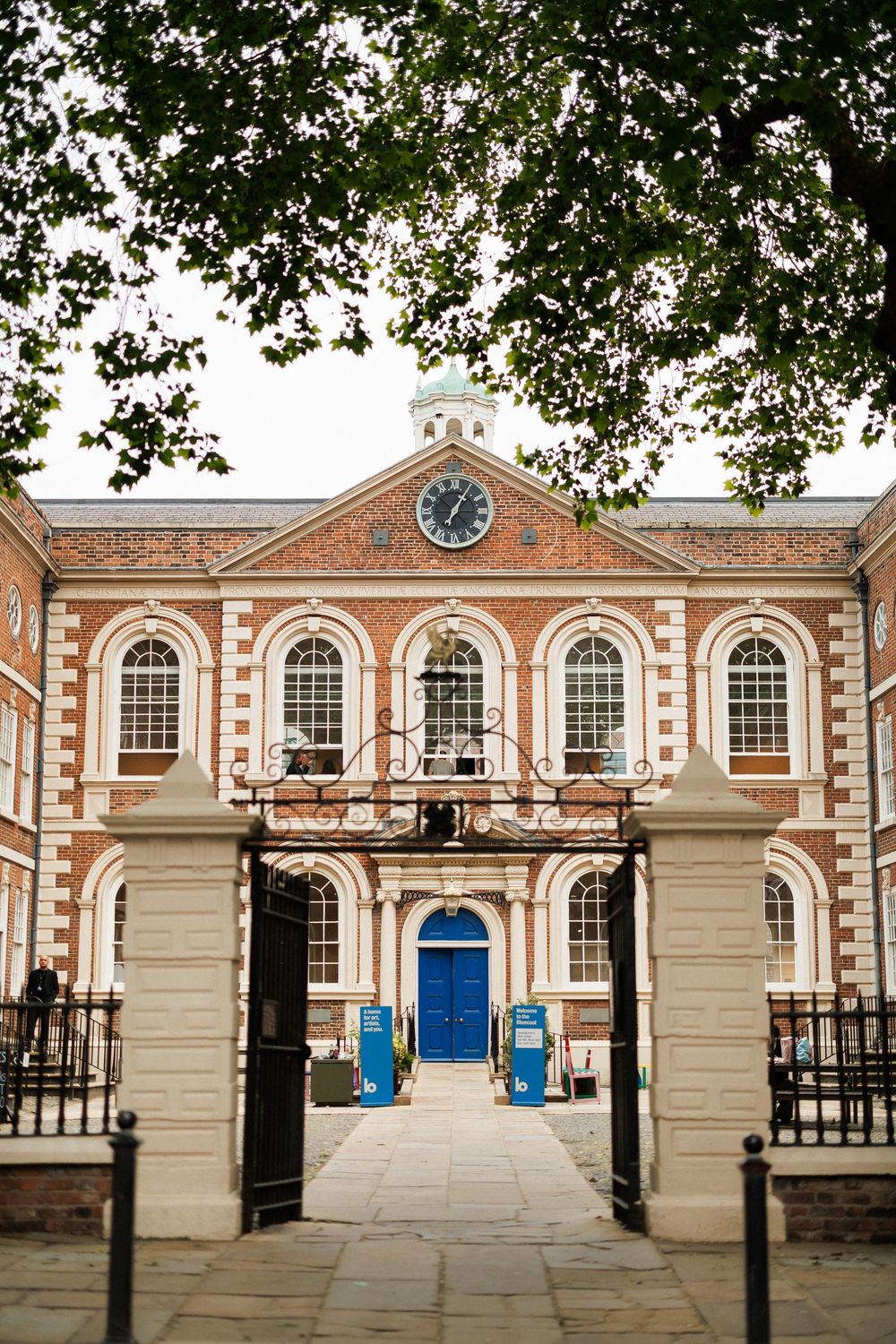 Historic Georgian brick building with blue door, arched windows, clock tower, and iron gates in London.