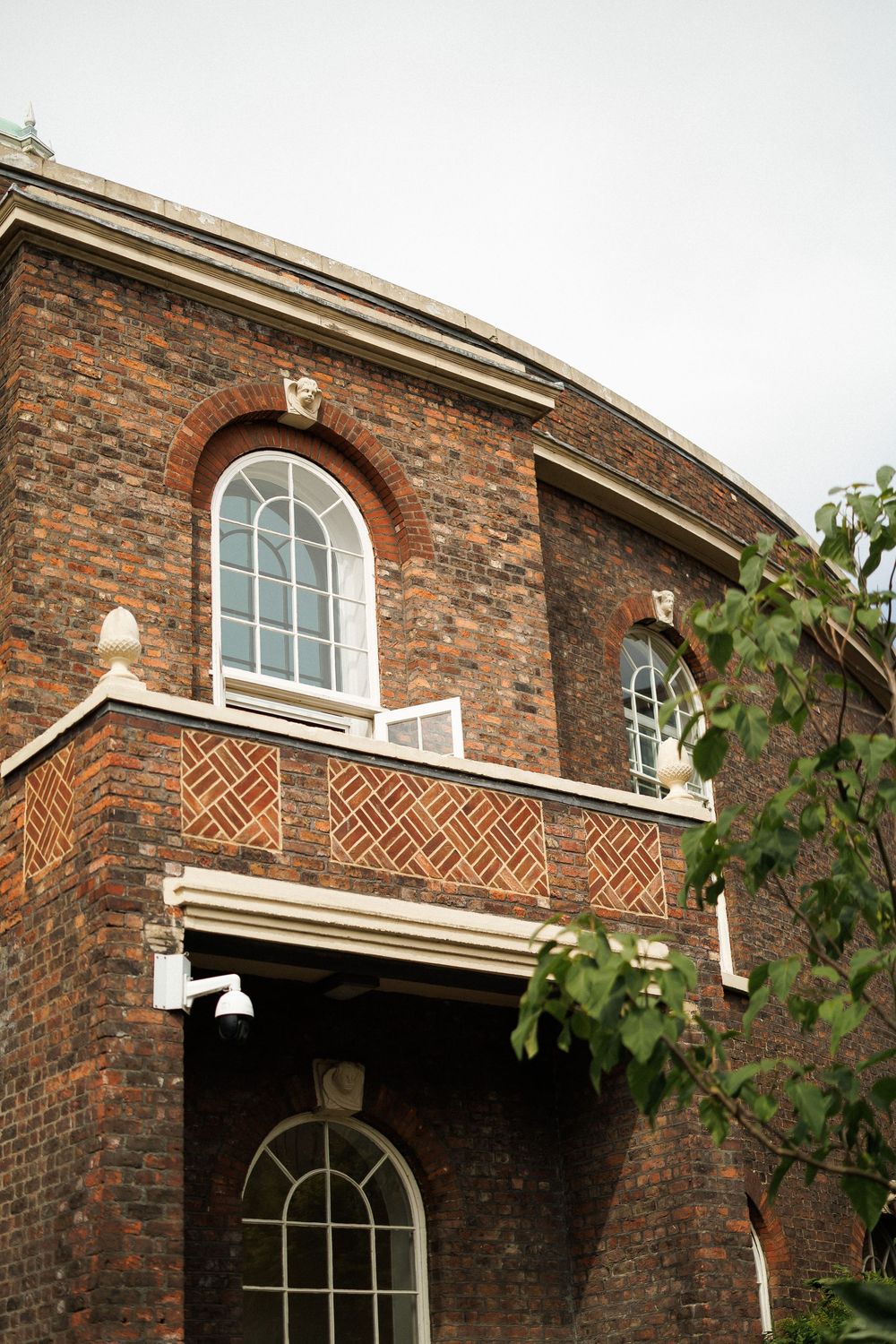 Exterior detail of a historic red brick wedding venue with decorative herringbone patterns and arched windows.