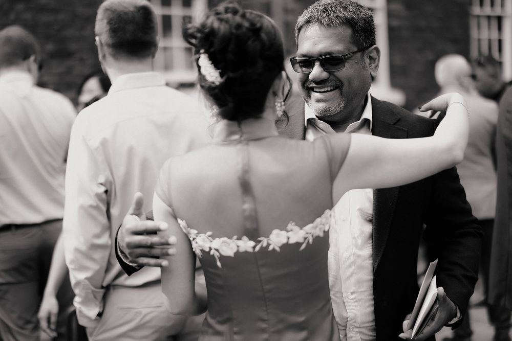 Black and white wedding photo of bride and groom embracing and smiling at outdoor reception.