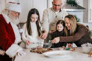 Family decorating Christmas cookies with Santa Claus in a bright kitchen during the holiday season.