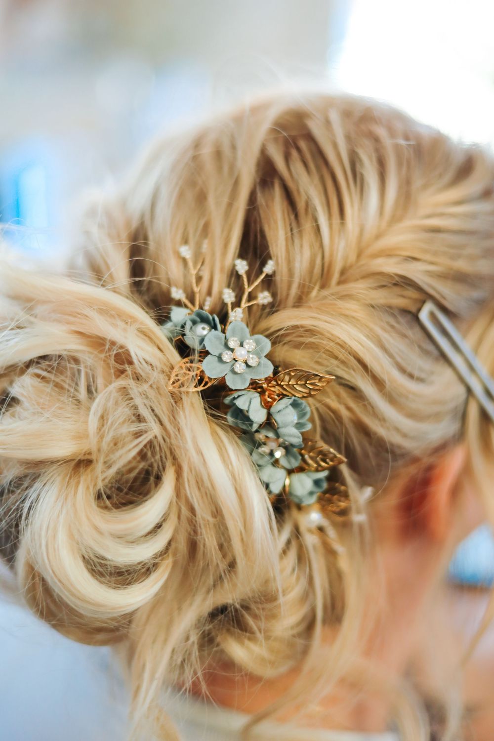 Elegant bridal updo with gold and blue floral hair accessory in blonde hair. getting ready pictures wedding day. western weddings