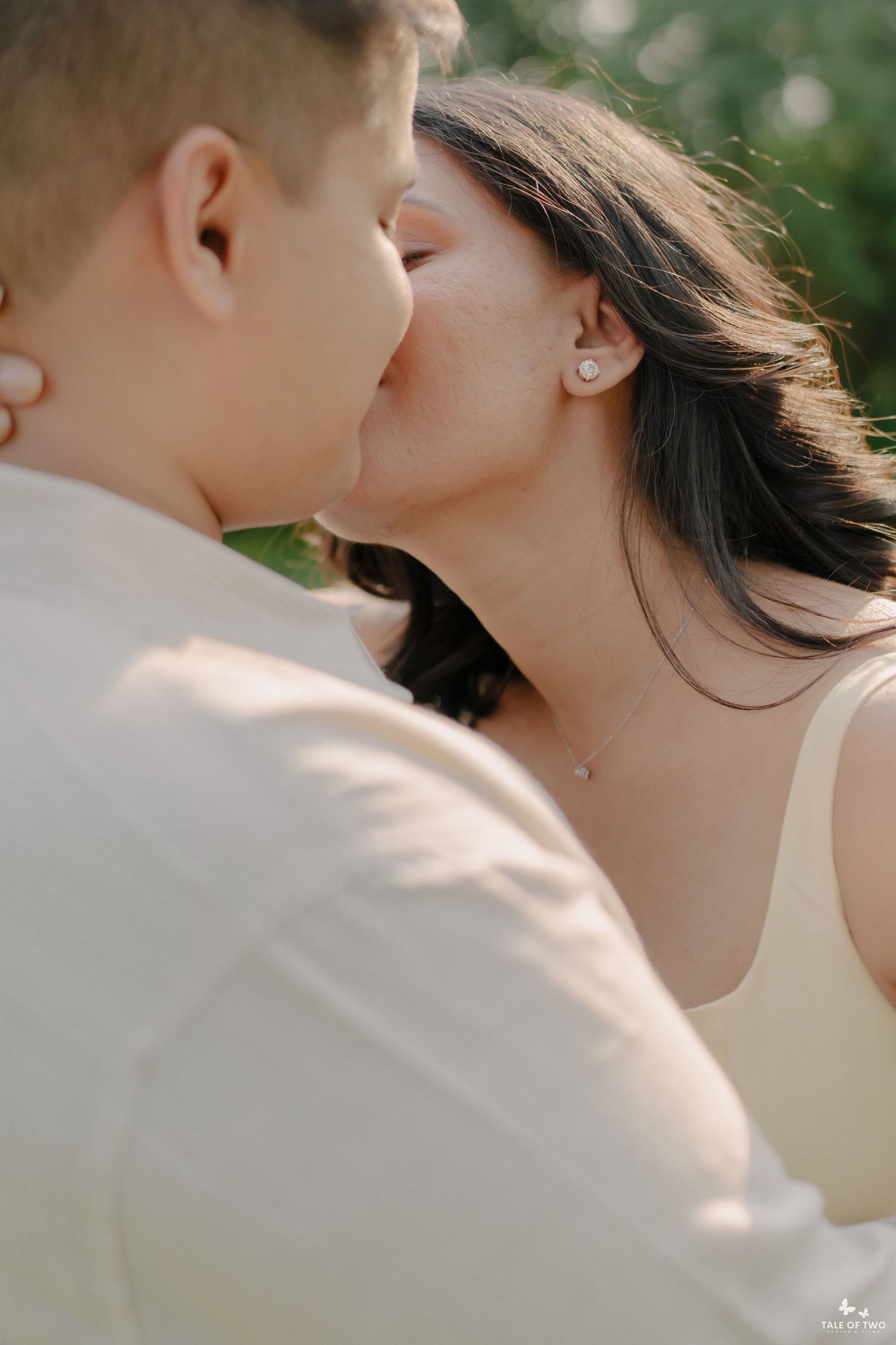 A couple shares a romantic kiss outdoors during a golden hour engagement photography session.