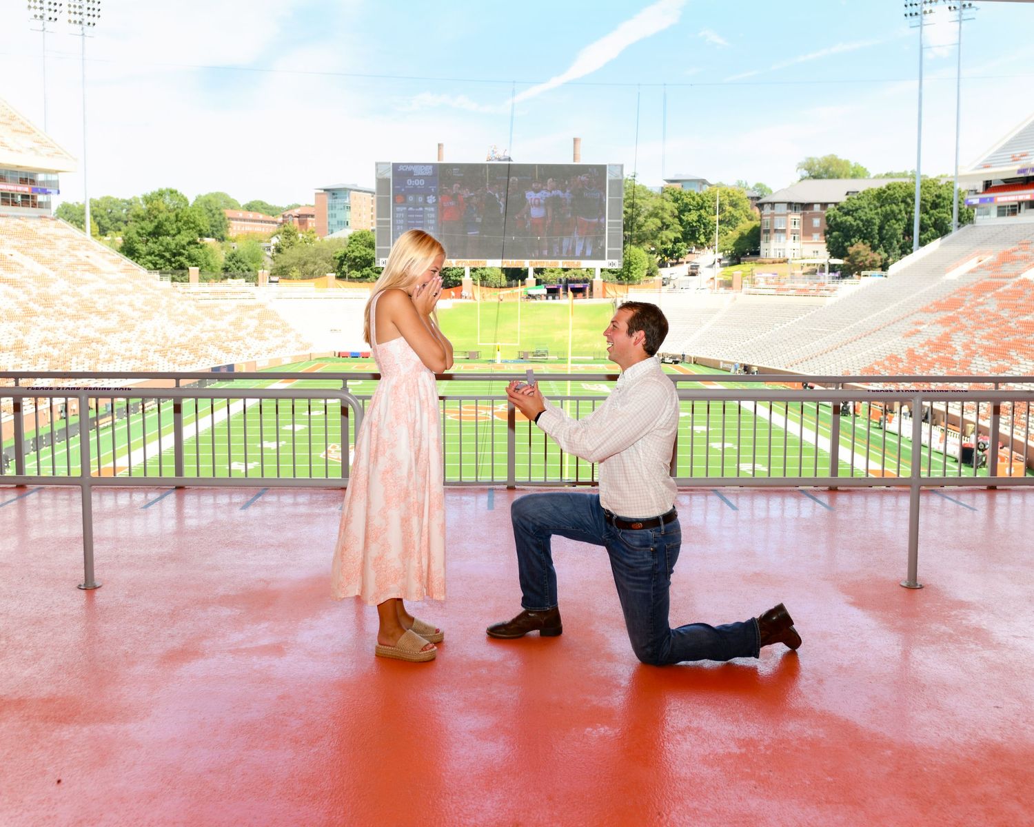 A romantic proposal moment captured at a stadium with sunset lighting.