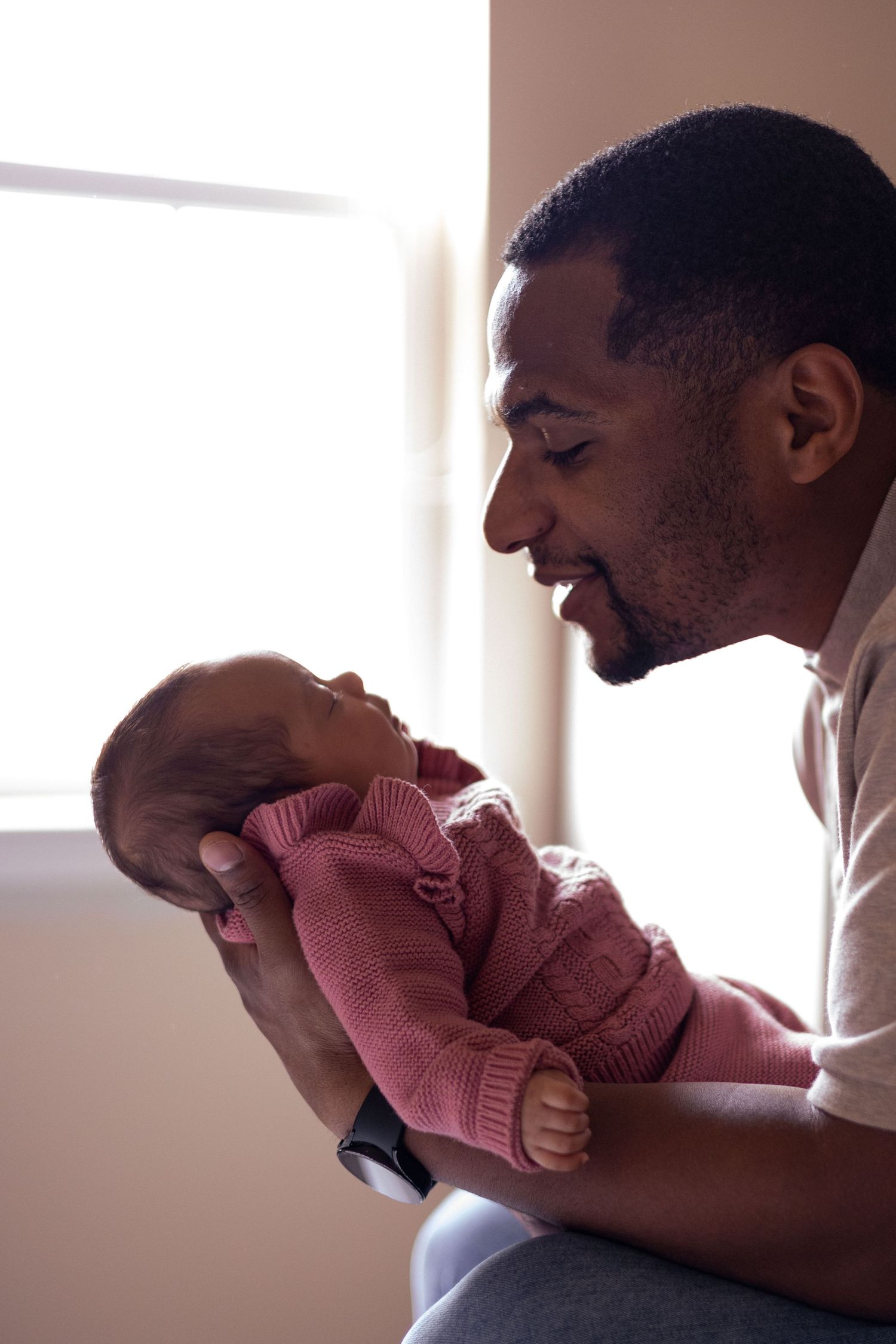 A dad looks lovingly at his newborn baby.