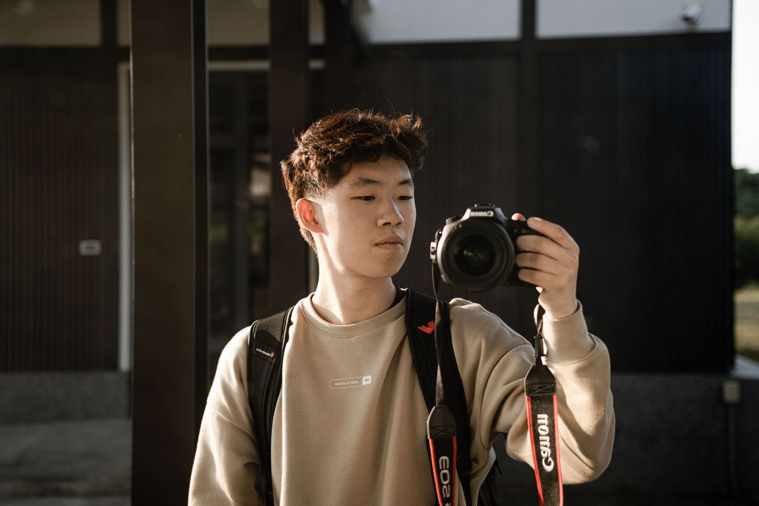 Photographer with camera in casual attire photographing in dim indoor setting.