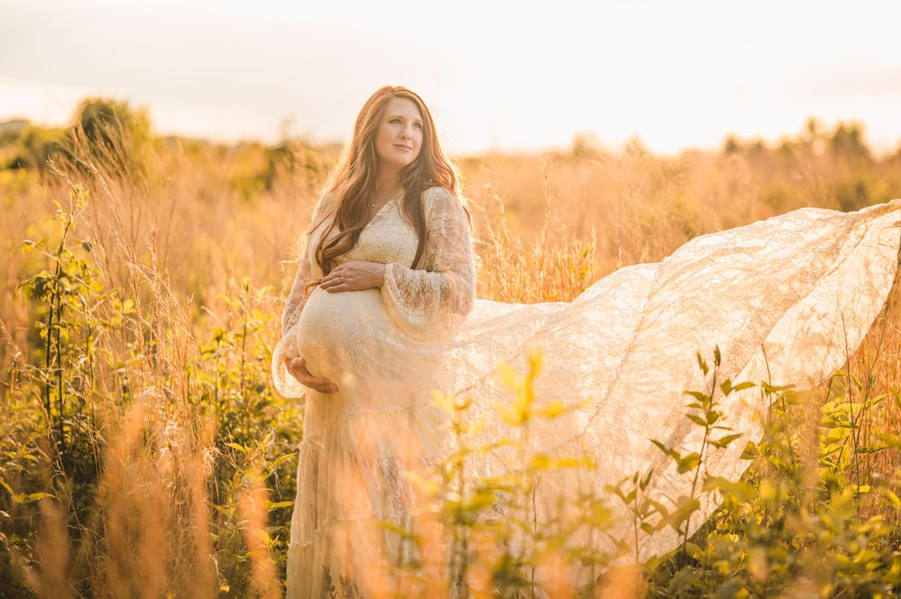Dreamy maternity portrait in a golden field during sunset.