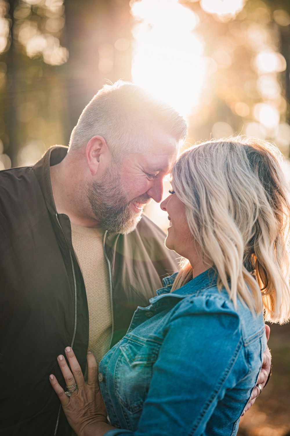 Intimate couples portrait with glowing sunset bokeh in forest setting.