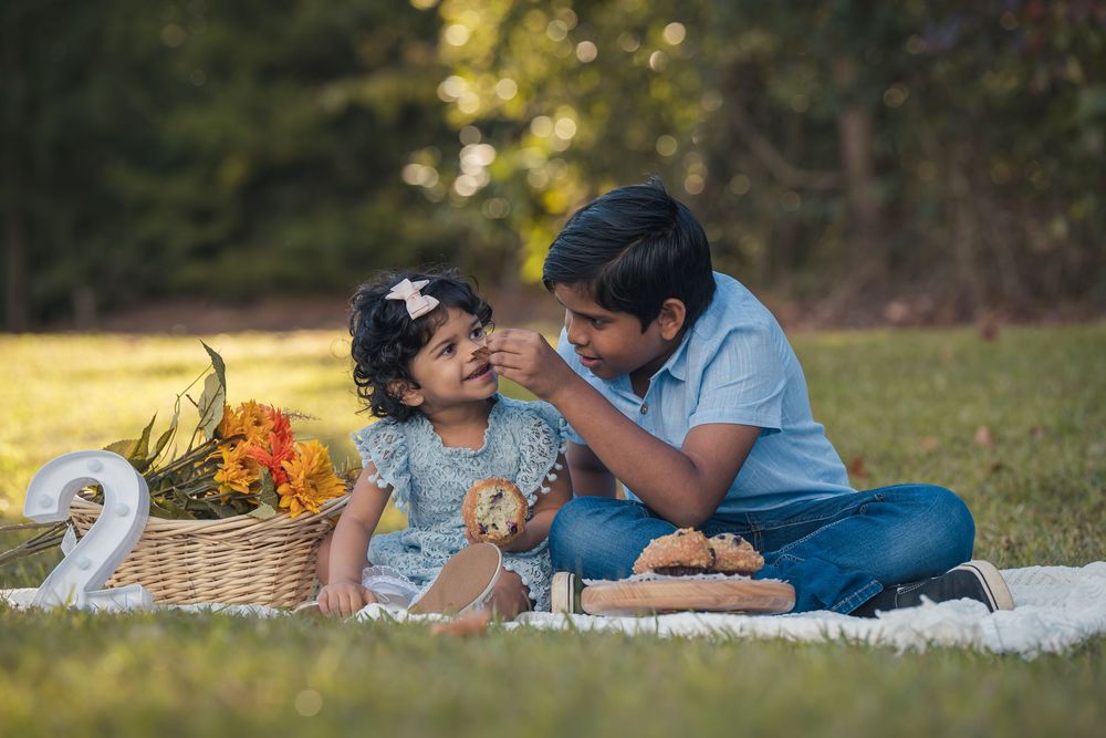 A couple lying on a blanket in the grass during a romantic outdoor picnic on a sunny afternoon.