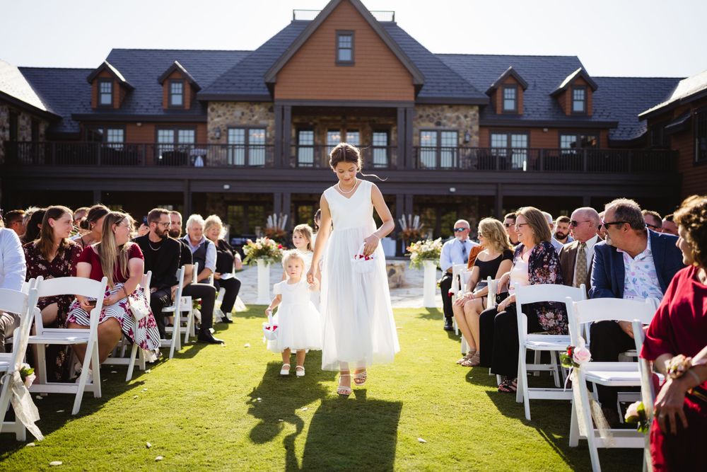 An outdoor wedding ceremony setup with white chairs and a large mansion in the background.