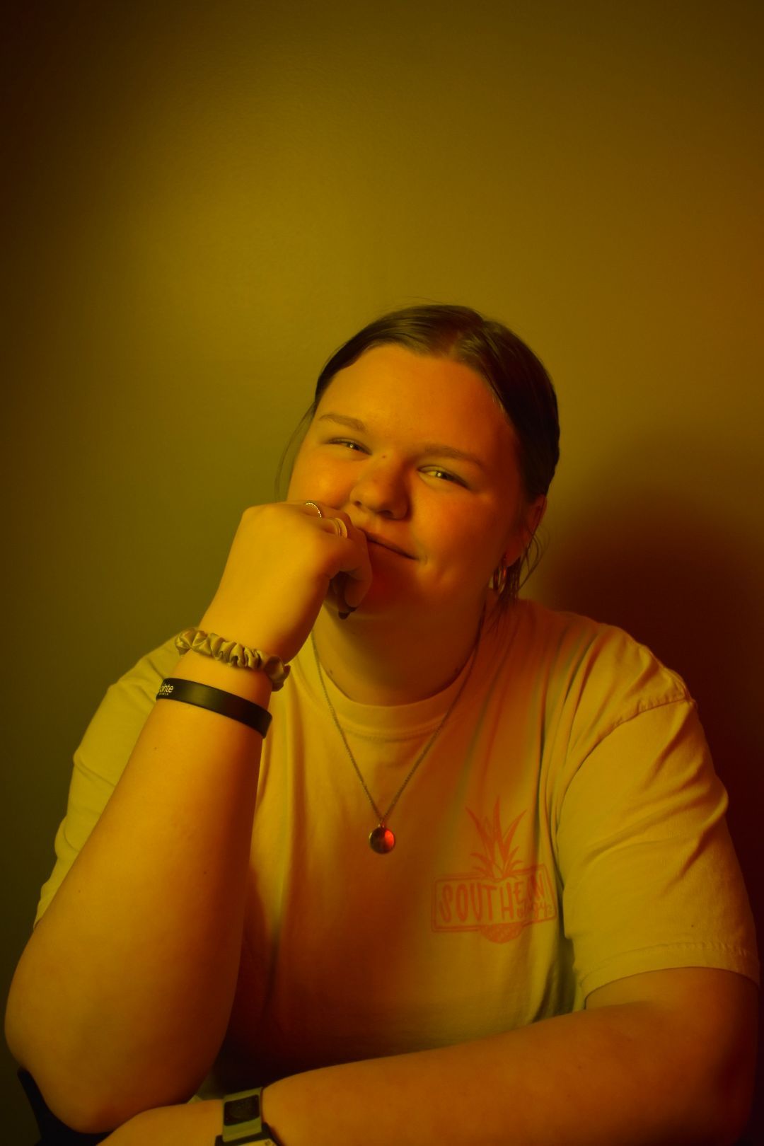 Portrait with golden lighting shows relaxed pose with hand resting on chin.