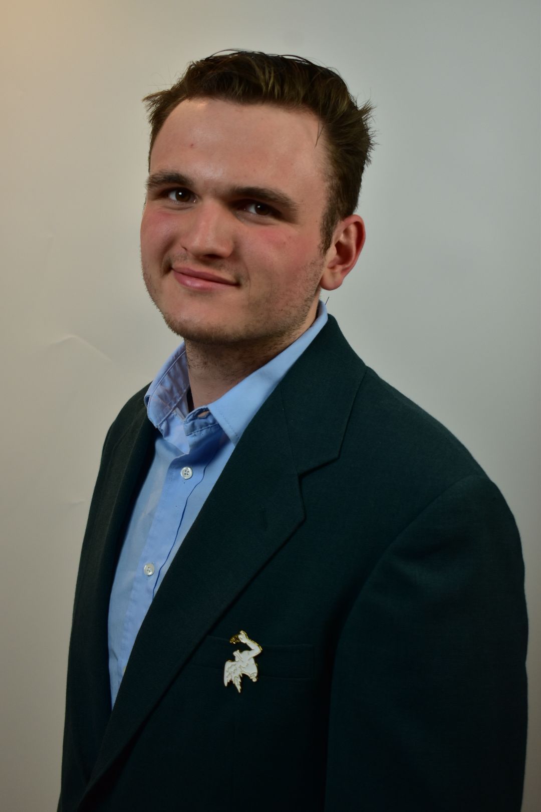Professional portrait of someone in navy blazer and light blue button-down shirt.