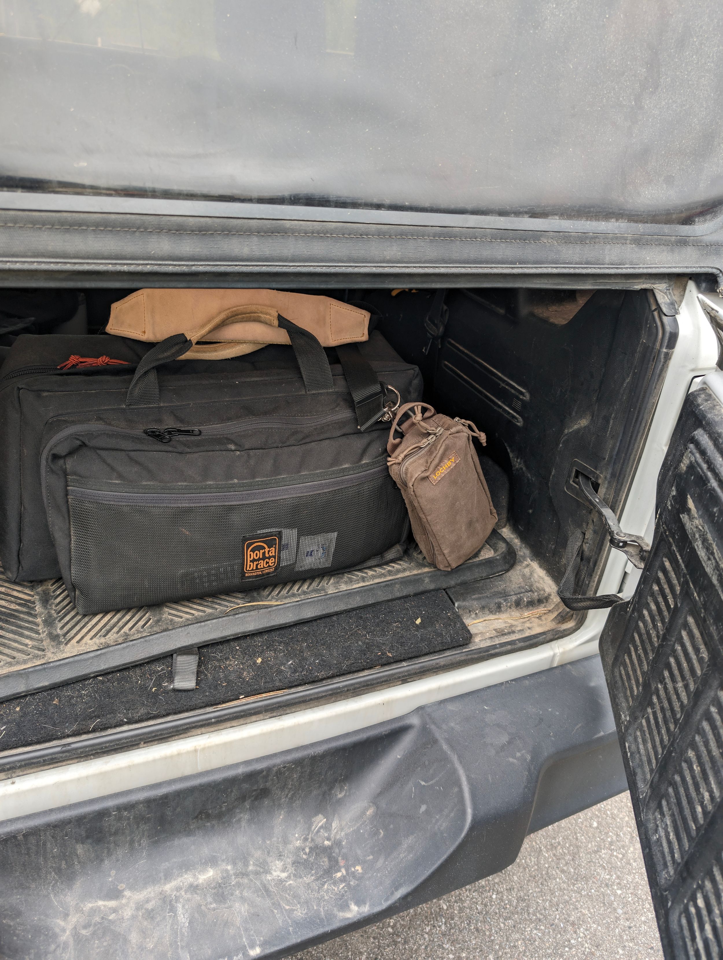 Various bags and gear stored in vehicle trunk compartment.