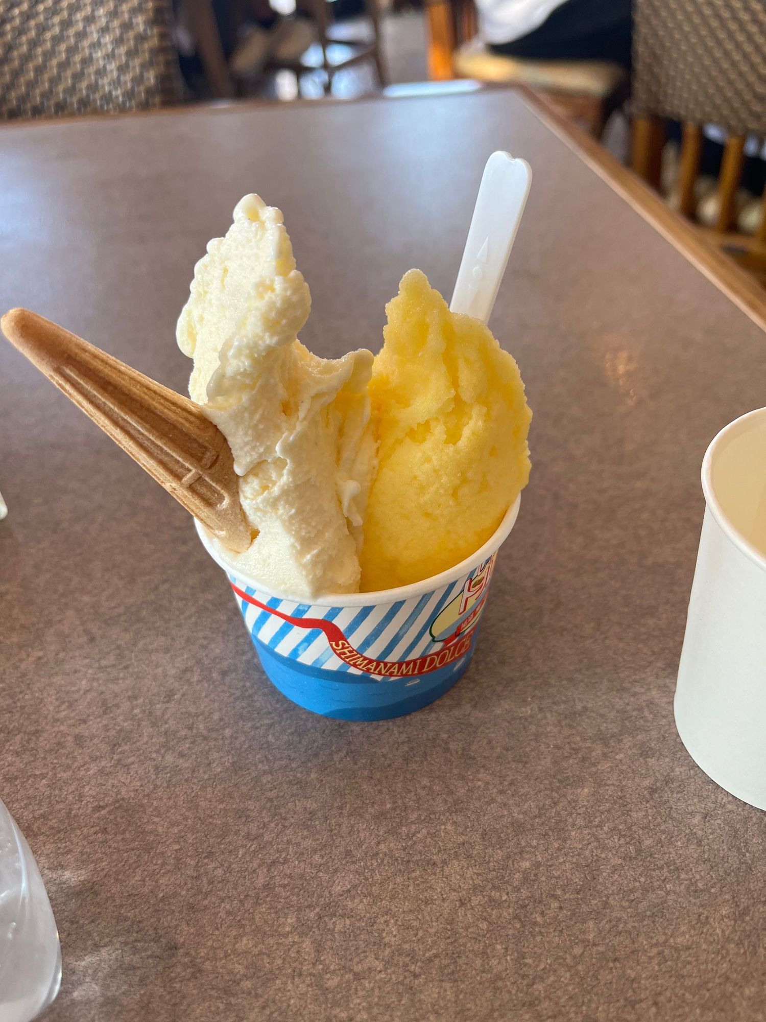 Soft serve ice cream in blue and white paper cups served on a brown surface.