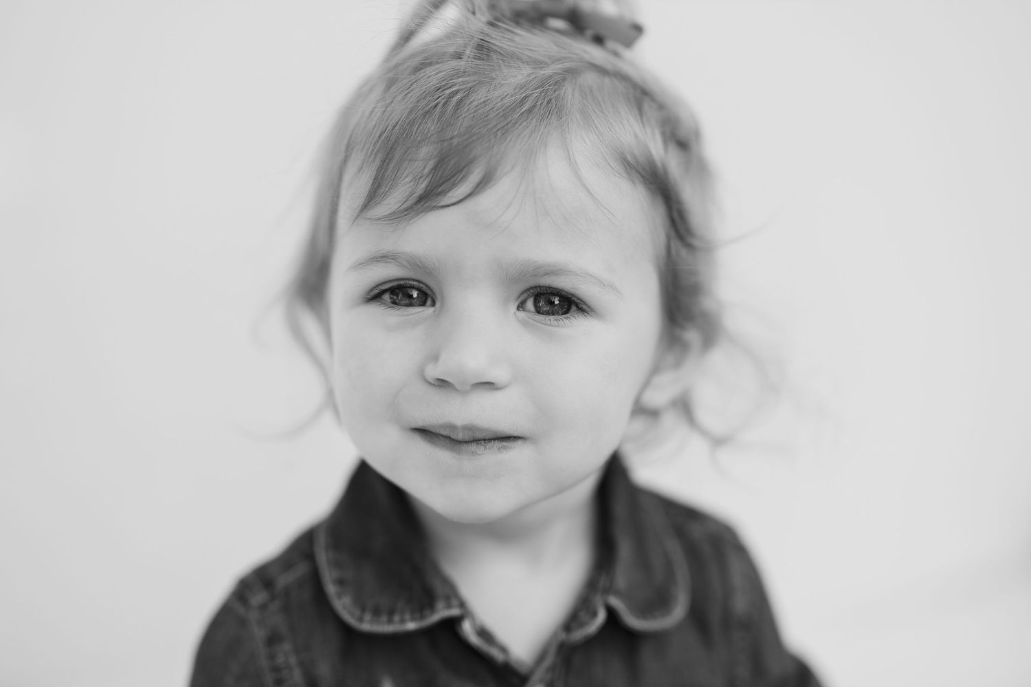 Black and white portrait of a young child with soft lighting and gentle expression.