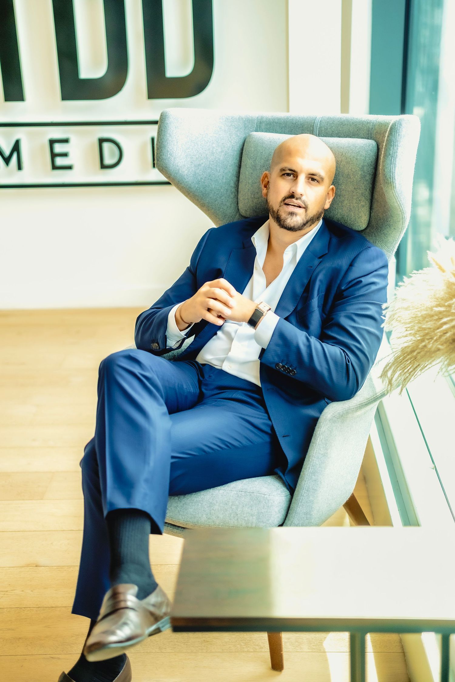 Professional in navy suit sitting in modern gray office chair at business office.