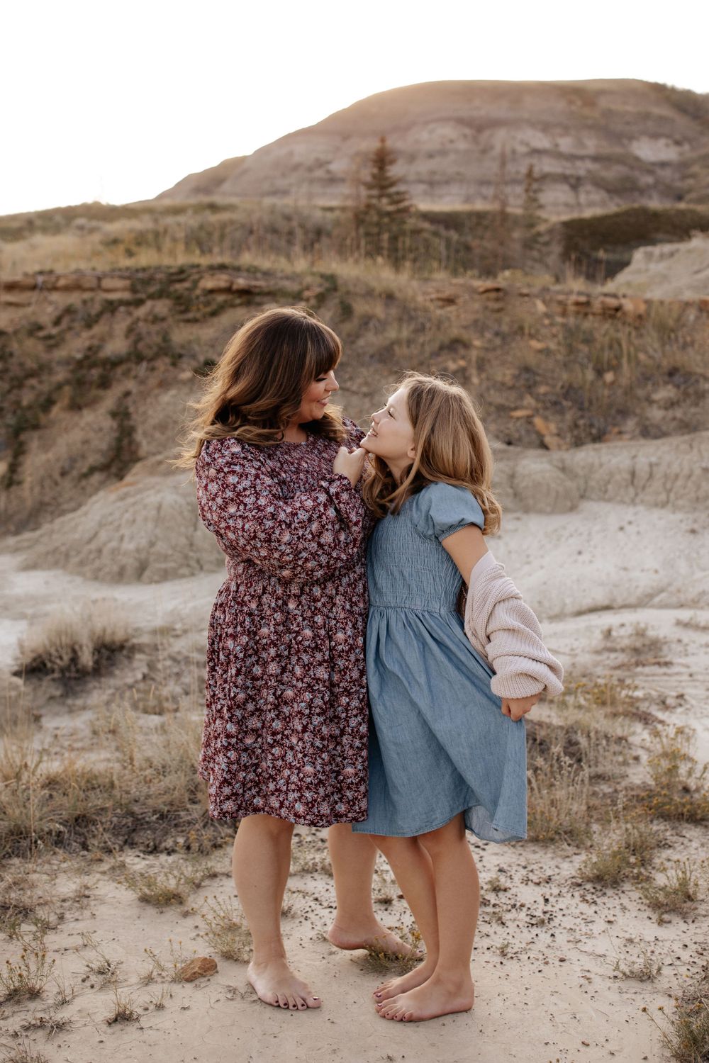 Children playing and running on sandy terrain near rocky cliffs.