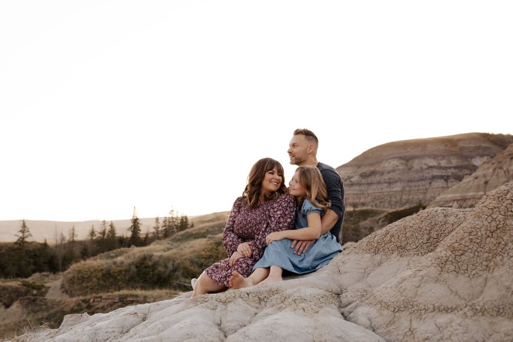 People relax together on a rocky hillside during sunset.