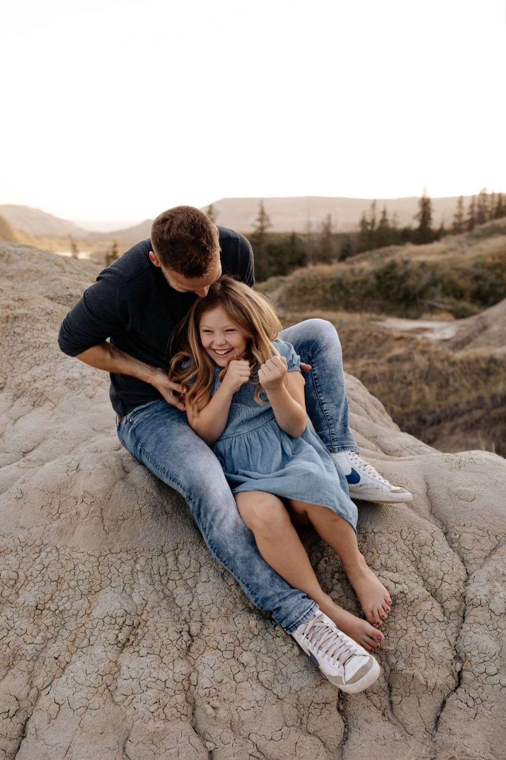 A couple shares laughter while lounging on rocky terrain at dusk.