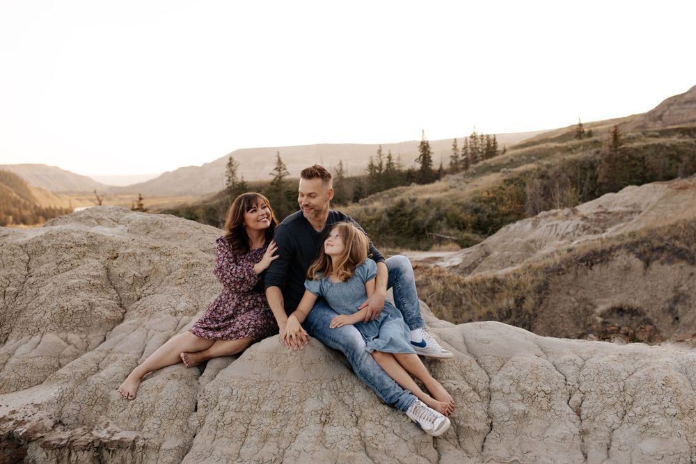 A family shares a playful moment together on rocky terrain at sunset.
