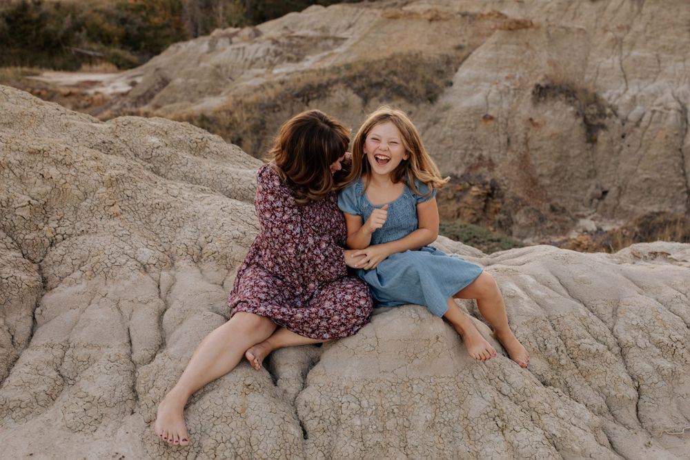 A family enjoys quality time together on rocky terrain during sunset.