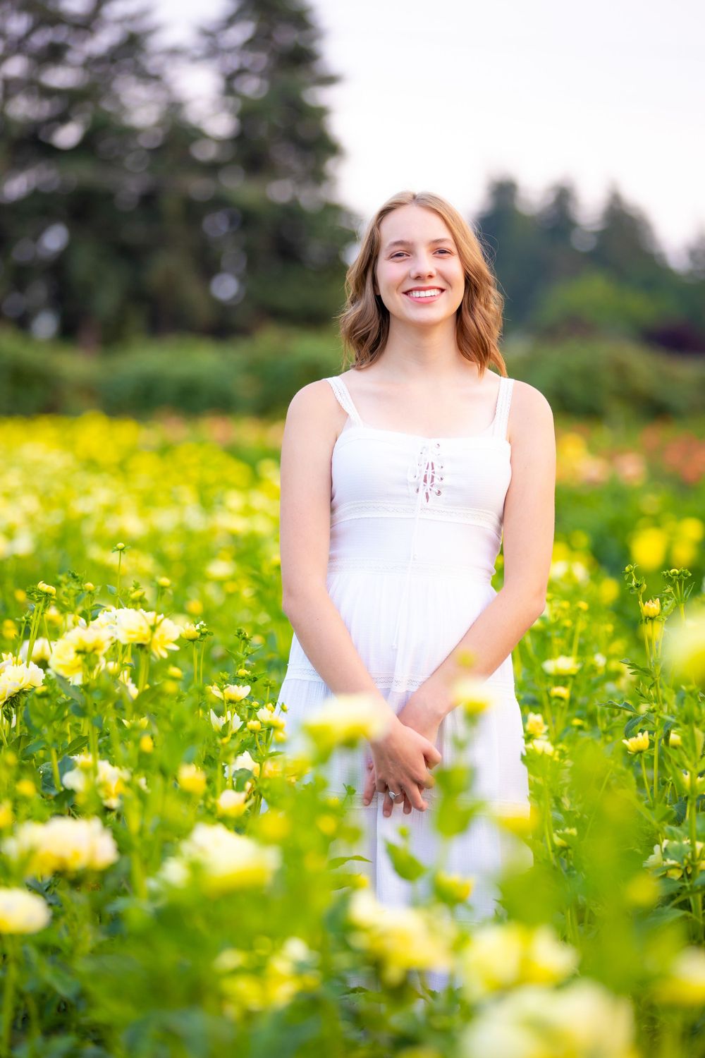A summer portrait in a field of yellow wildflowers on a sunny day.
