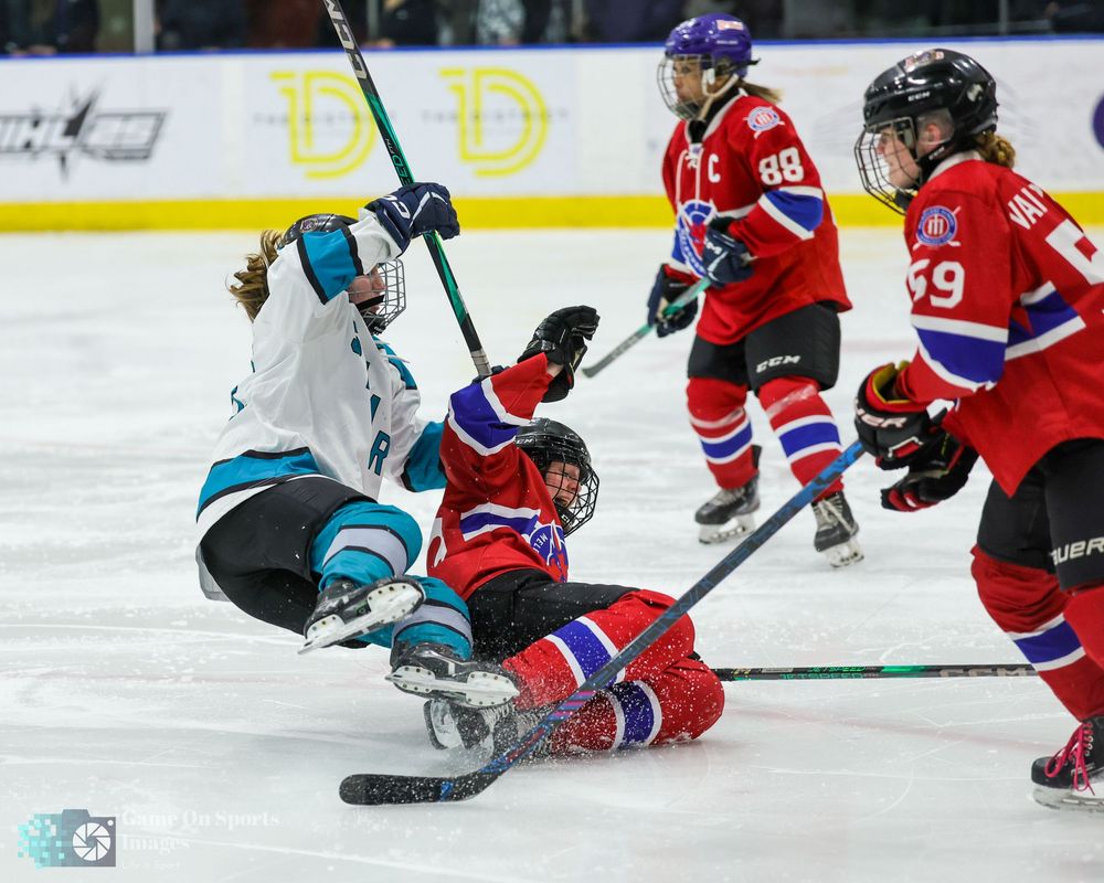 Female ice hockey players in red and teal uniforms collide on the ice during an intense professional game.