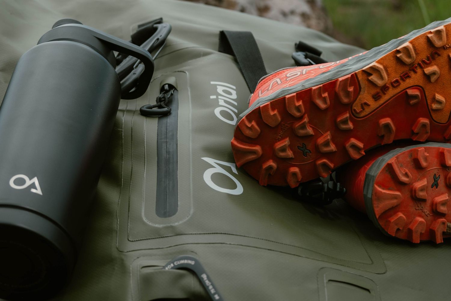 Close up of hiking boots with orange laces on rugged outdoor terrain.