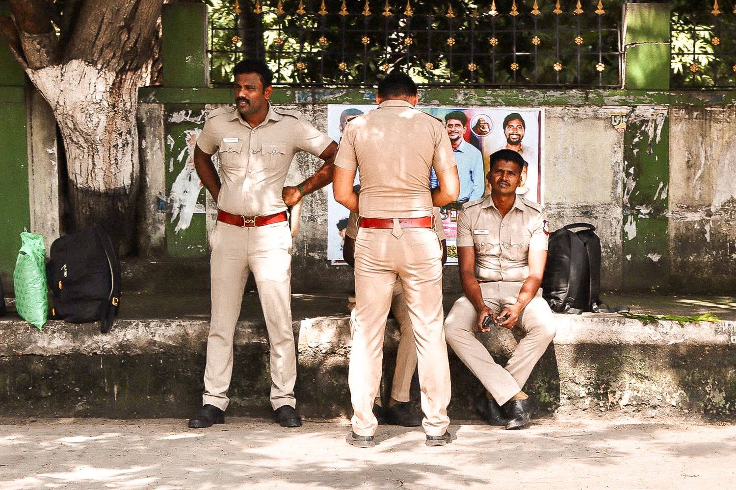 Group of Indian police officers standing and sitting outside a shaded wall in Delhi