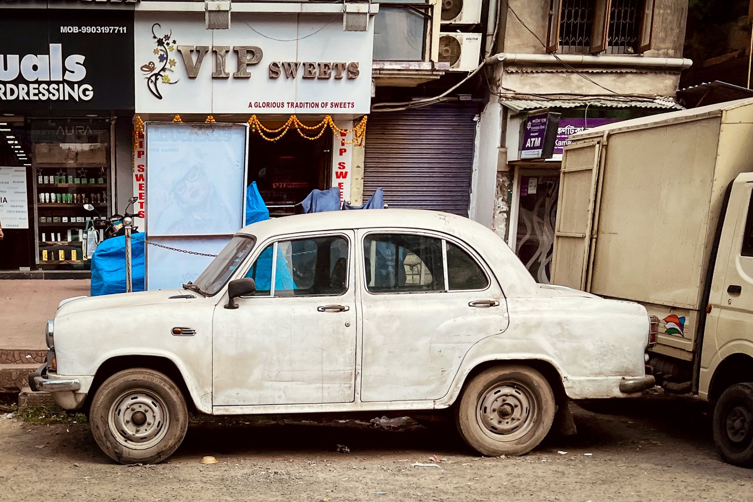 White Ambassador car parked in front of VIP Sweets shop in an Indian town in Kolkata