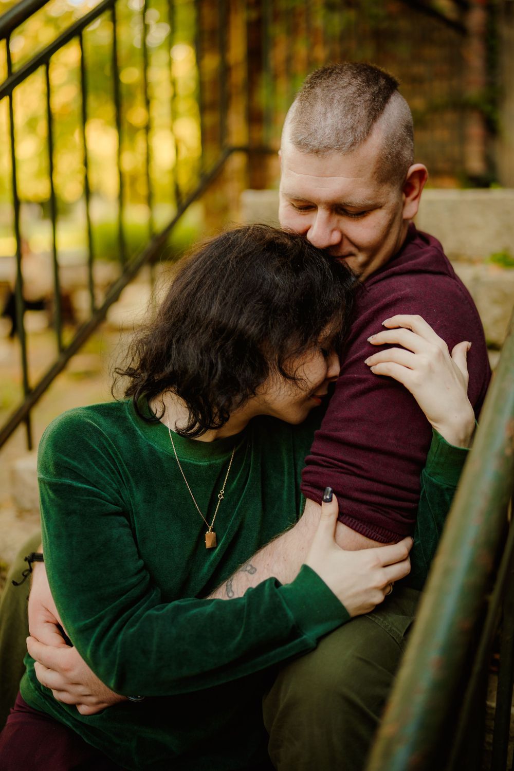 Tender embrace captured in warm autumn lighting on stone staircase.