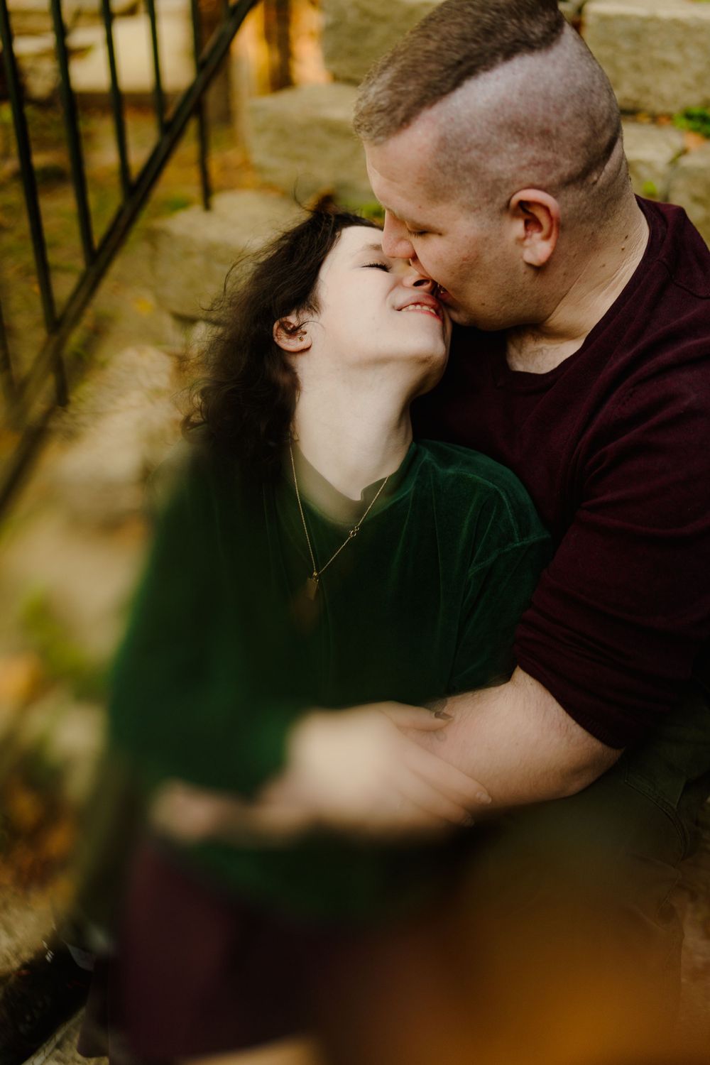 Intimate moment captured against rustic stone architecture in warm lighting.