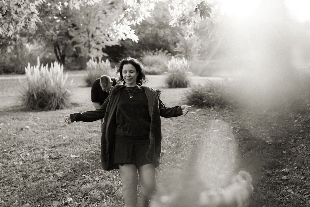 A joyful moment captured in black and white of someone posing playfully in a sunny garden.