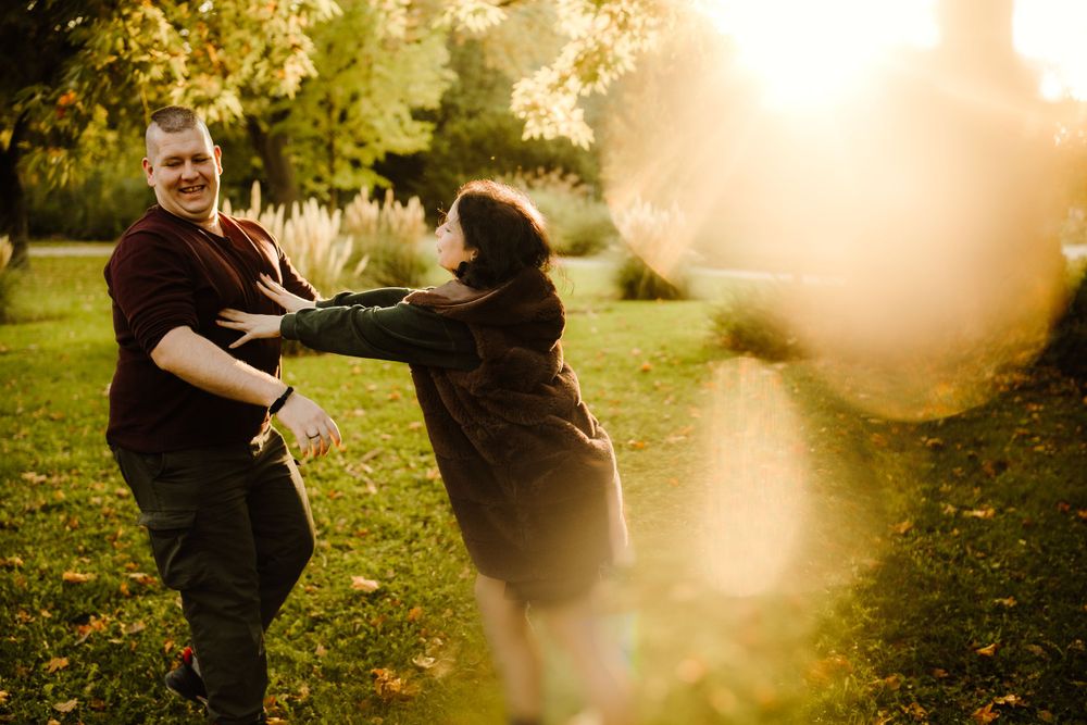 A couple shares a playful moment together in a sunlit garden setting.