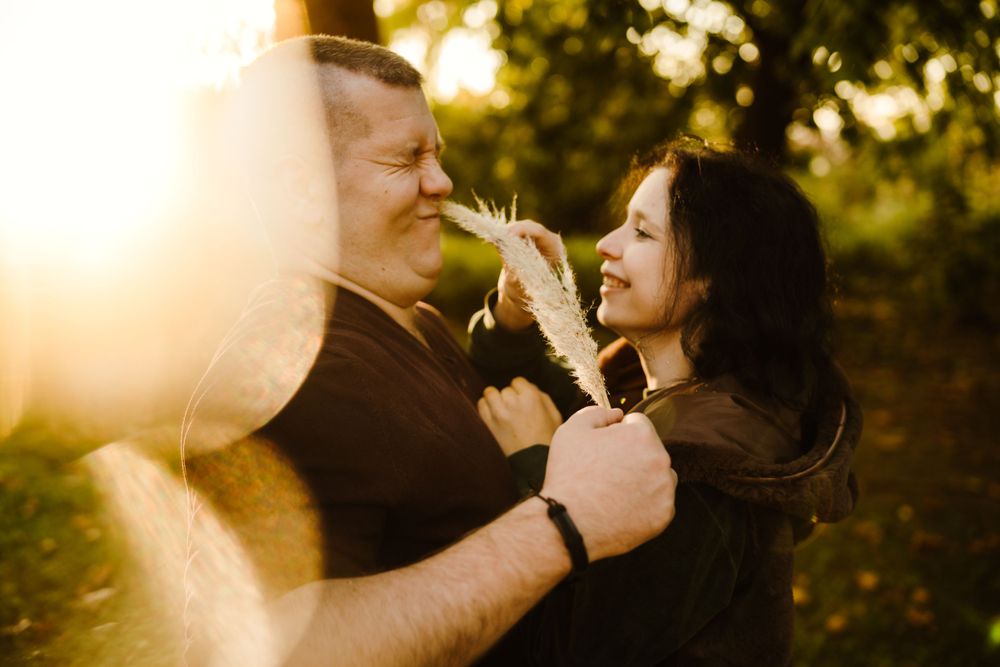 A romantic moment between two people holding dandelions in golden sunlight.