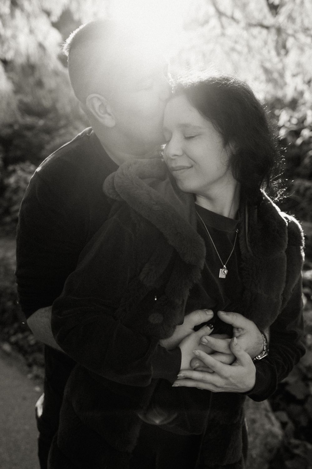 Intimate black and white portrait of a couple embracing in soft natural light.