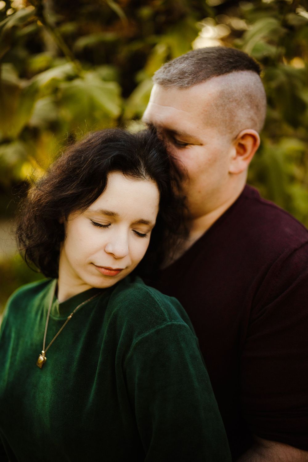 Close-up of a couple in burgundy and green velvet sharing a quiet moment outdoors.