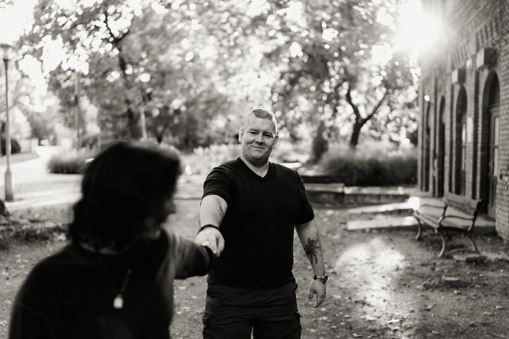 Black and white candid photo showing dynamic interaction between two people outdoors.