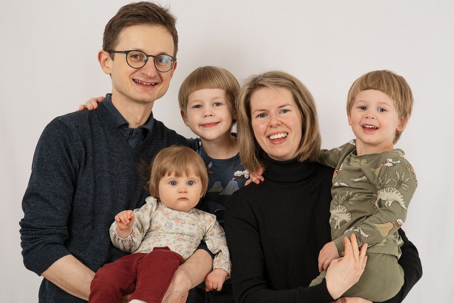 Ett ömt familjeögonblick fångat i gyllene timmen, när föräldrar delar en kyss med sin bebis mellan sig. - Fotograf Emma Matkoski