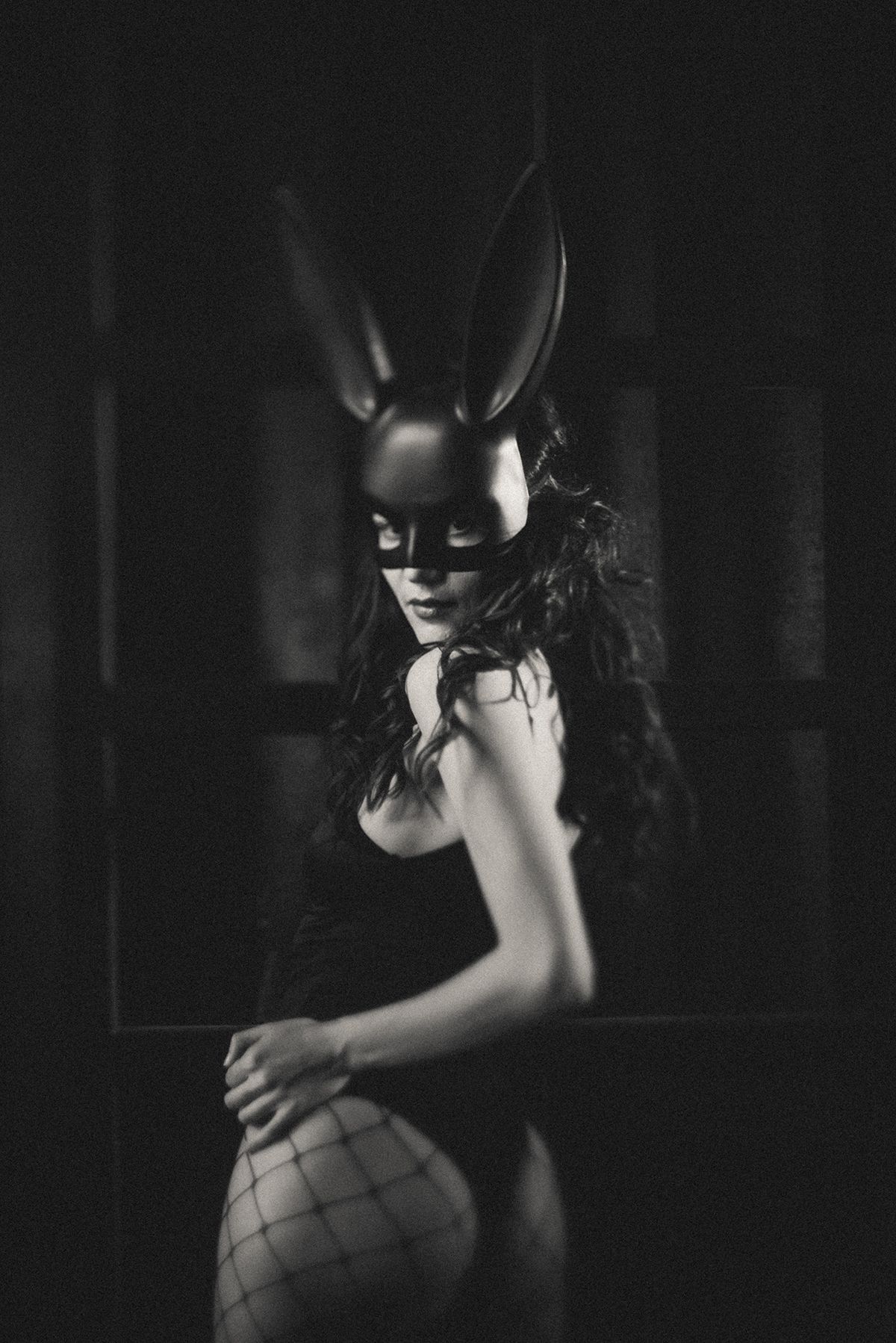 Artistic black and white portrait featuring a dark mask and dramatic shadows.