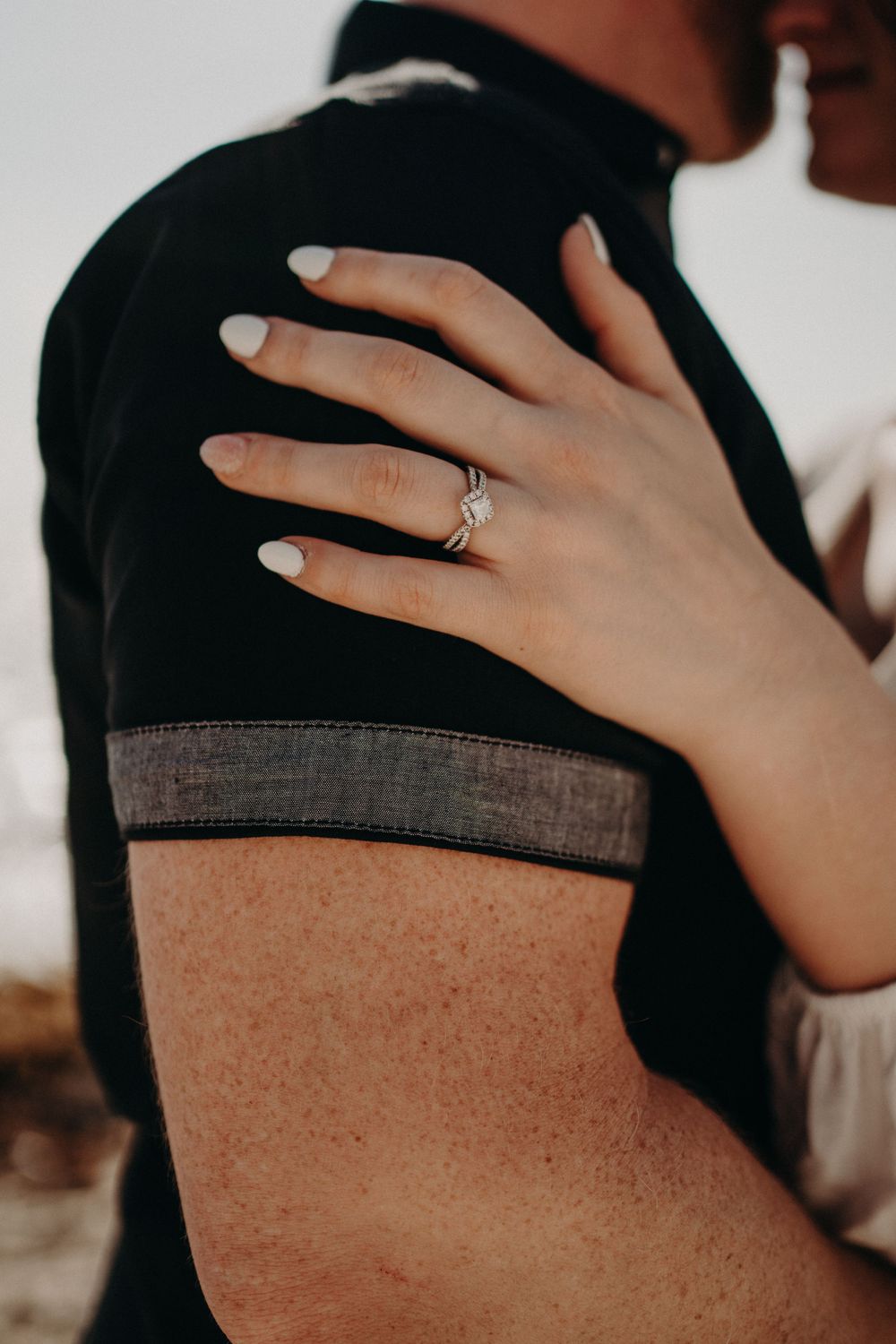 Close-up of a hand with white nail polish and engagement ring resting on a black shirt photoshoot in Puerto Morelos.