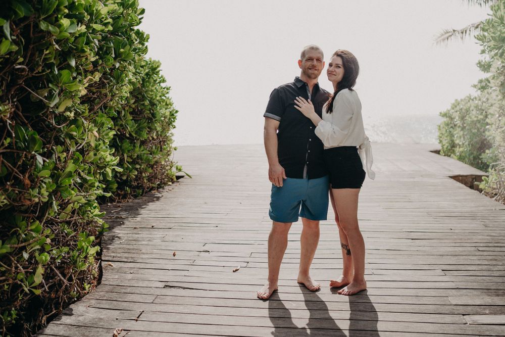 A romantic couple standing on a wooden boardwalk surrounded by lush greenery photoshoot in Puerto Morelos.