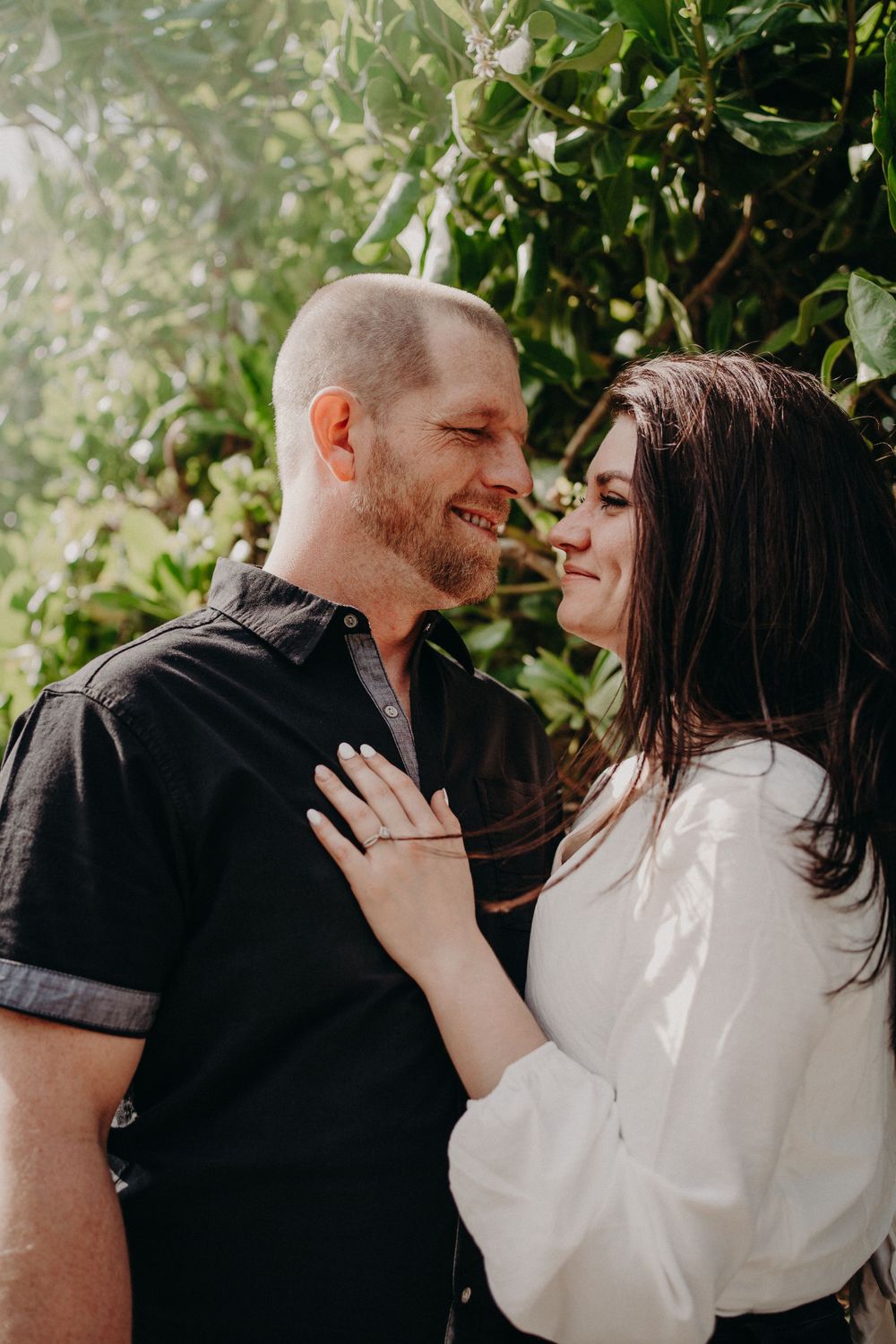 An intimate moment between a couple sharing laughter against a leafy backdrop photoshoot in Puerto Morelos.